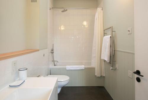 a white bathroom with a toilet and a bath tub at Lynchets in Dorchester