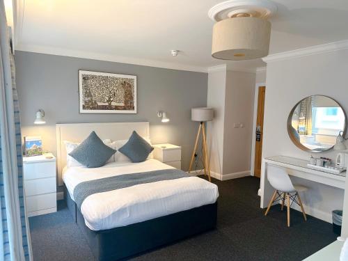 1 dormitorio con cama, escritorio y espejo en Legends Hotel en Brighton & Hove