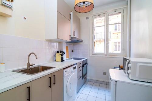 une cuisine blanche avec un évier et un lave-vaisselle dans l'établissement Charmant Appartement au Cœur de Neuilly-sur-Seine, à Neuilly-sur-Seine