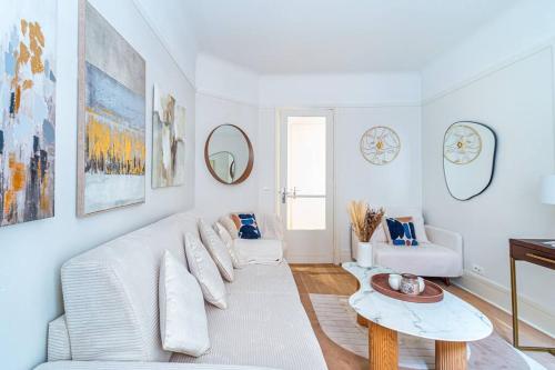 un salon blanc avec un canapé blanc et une table dans l'établissement Charmant Appartement au Cœur de Neuilly-sur-Seine, à Neuilly-sur-Seine