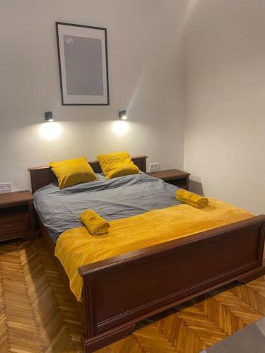 a bedroom with a bed with yellow pillows on it at Maros Apartman in Budapest