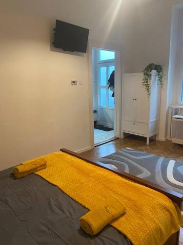 a bedroom with a bed with a yellow blanket on it at Maros Apartman in Budapest