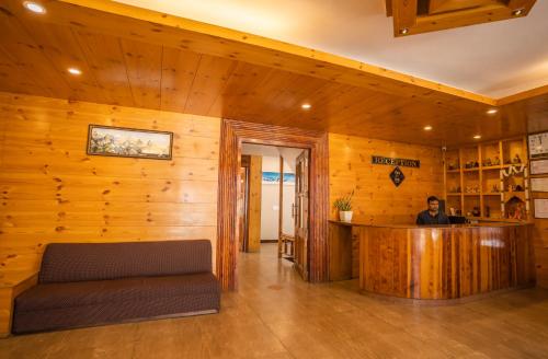 a man sitting at a bar in a room with wooden walls at THE CONIFER in Manāli