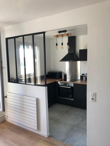 - une cuisine avec des comptoirs en noir et blanc et une cuisinière dans l'établissement Studio cosy vue cathédrale, à Reims