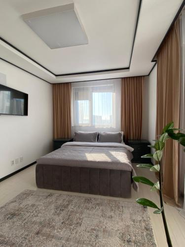 um quarto com uma cama grande e uma janela grande em Хайвилл парк однокомнатные апартаменты em Astana