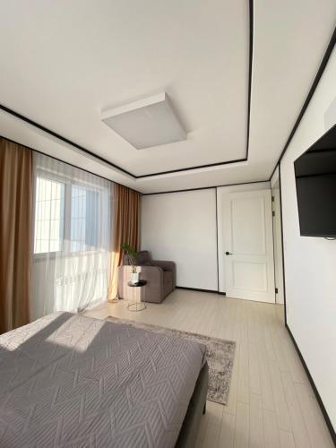 um quarto com uma cama, uma televisão e um sofá em Хайвилл парк однокомнатные апартаменты em Astana