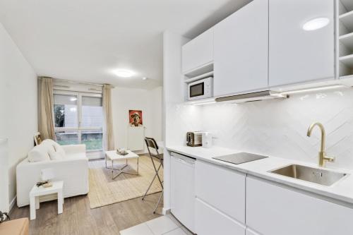 eine Küche mit weißen Schränken und ein Wohnzimmer in der Unterkunft Chic studio Appartment in Rosny-sous-Bois