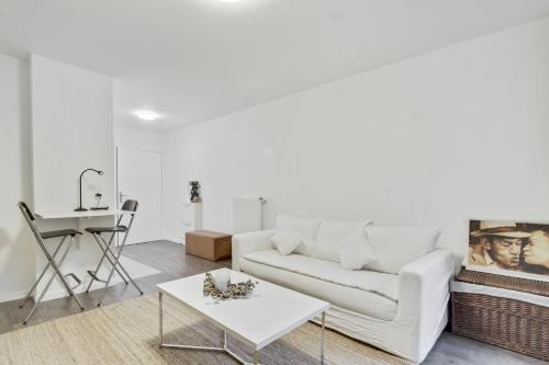un salon avec un canapé blanc et une table dans l'établissement Chic studio Appartment, à Rosny-sous-Bois