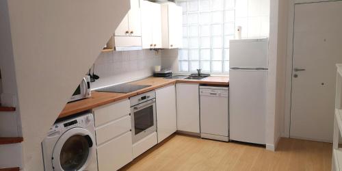 a kitchen with white cabinets and a washer and dryer at Somo Playa Vistas in Somo