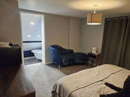 a bedroom with a bed and a chair and a tub at Startop Farmhouse in Marsworth