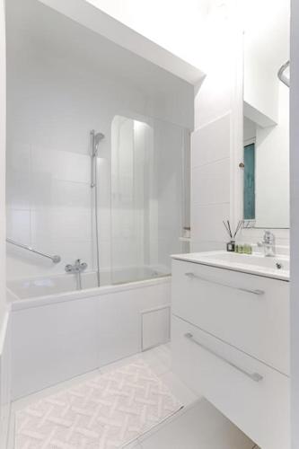 une salle de bain blanche avec une douche et un lavabo dans l'établissement Matignon Saint-Honoré : Magnifique Appartement 1BR, à Paris
