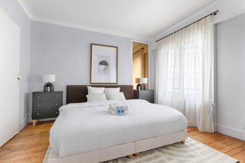 une chambre blanche avec un grand lit et une fenêtre dans l'établissement Matignon Saint-Honoré : Magnifique Appartement 1BR, à Paris
