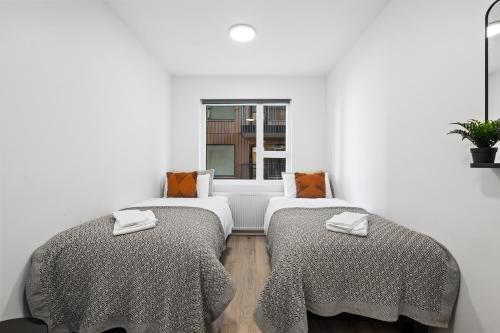 two beds in a white room with a window at Unwind in Luxury Steps From Smáralind Mall in Reykjavík