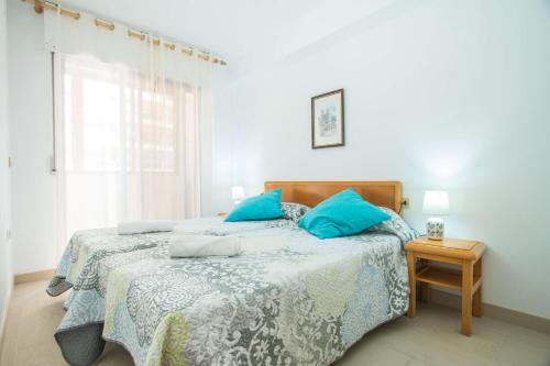 a bedroom with a bed with blue pillows on it at Apartamento Calpeplaya - PlusHolidays in Calpe