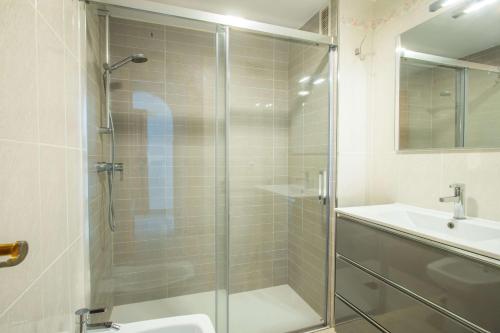a bathroom with a glass shower and a sink at Apartamento Calpeplaya - PlusHolidays in Calpe
