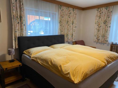 a bed with a yellow comforter and a window at Haus Jochbergerstrasse 116 in Kitzbühel