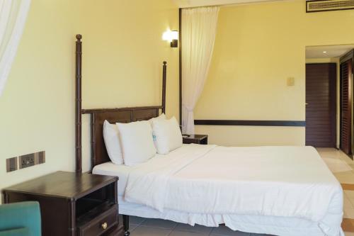 a bedroom with a large white bed and a desk at Mombasa Continental Resort in Shanzu