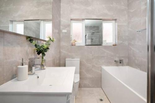 a bathroom with a sink and a tub and a toilet at Delightful Home with Amazing city views! in Sydney