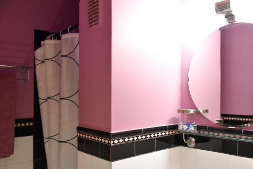 La salle de bains est pourvue d'un mur rose et d'un miroir. dans l'établissement Colourful Apt in Nea Smyrni, à Athènes