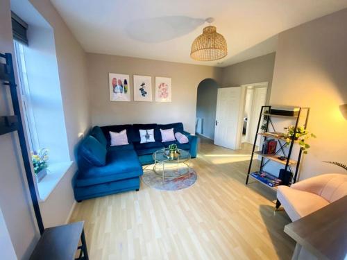 a living room with a blue couch and a glass table at City Centre Riverside Apartment in Winchester