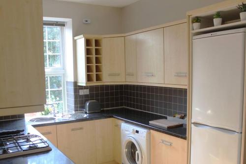 cocina con nevera blanca y lavadora en City Centre Riverside Apartment, en Winchester