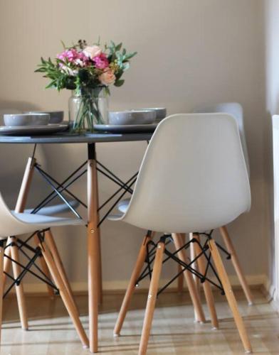 a table with a vase of flowers and two chairs at City Centre Riverside Apartment in Winchester