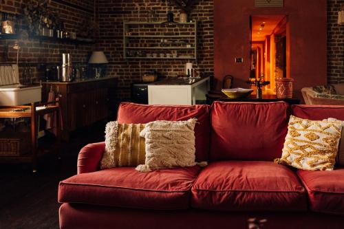 um sofá vermelho com almofadas numa sala de estar em The George & Heart House em Kent