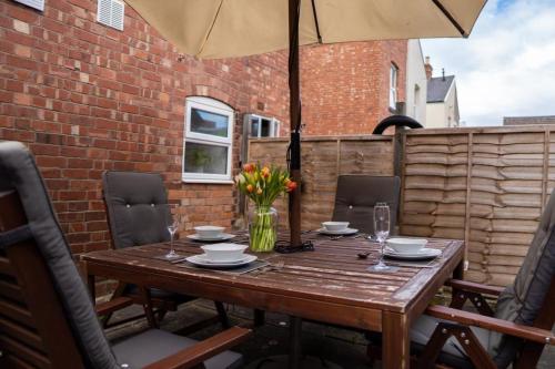 a wooden table with chairs and an umbrella at Central 6Bed Retreat - Your Perfect Coventry Holiday Home Away in Coventry
