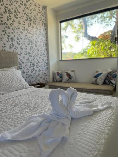 a white blanket laying on a bed with a window at Village Ninho da Jandaia in Mata de Sao Joao