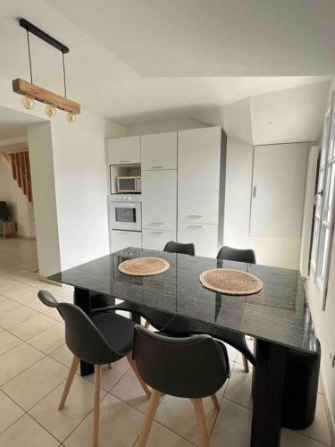 une table de salle à manger avec des chaises et une cuisine dans l'établissement Le Brèche, appartement spacieux, Orléans Sud, à Orléans