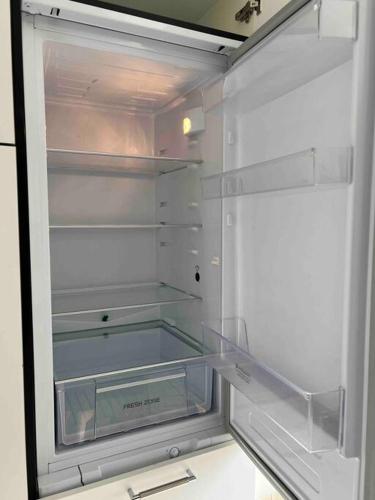 un réfrigérateur vide avec une porte ouverte dans une pièce dans l'établissement Le Brèche, appartement spacieux, Orléans Sud, à Orléans