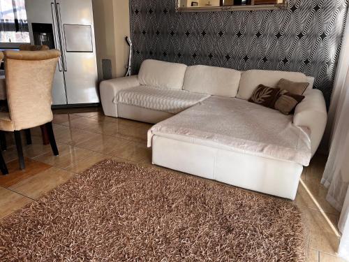 ein Wohnzimmer mit einer weißen Couch und einem Teppich in der Unterkunft Airport Road/Reptér közeli ház privát parkolóval in Budapest
