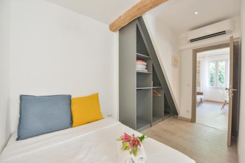 a room with a bed with a yellow and blue pillow at LE PETIT CASTELET - New superb flat in old Antibes, AC, WIFI, for 4 in Antibes