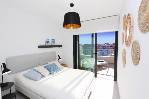 a white bedroom with a bed and a balcony at Flamenca Village south facing close to the beach (VDE-045) in Orihuela