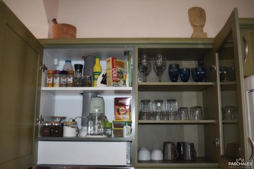a kitchen cabinet filled with lots of food and drinks at Delfi's cozy maisonette in Delfoi