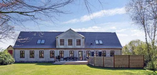 a large white house with a blue roof at Lovely Farmhouse For The Whole Family in Slagelse