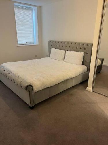 a large bed in a room with a mirror at Stylish Luxury new 2 bedroom Apartment in Dartford