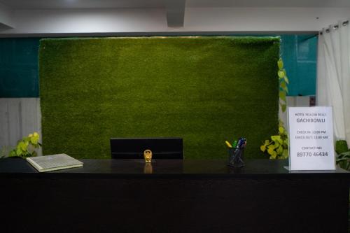 an office with a green wall and a desk with a book at Yellow Bells Gachibowli in Hyderabad