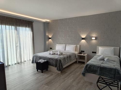 sypialnia z 2 łóżkami i dużym oknem w obiekcie Oikos 9 Rooms and Suites w mieście Nafpaktos