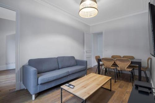 un salon avec un canapé bleu et une table dans l'établissement Appart 6Pers #3 bedrooms #2 Bathrooms#Paris 17ème, à Paris