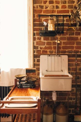 a kitchen with a sink and a brick wall at The George & Heart House in Kent