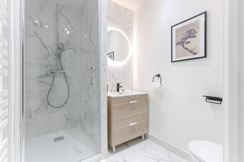 a white bathroom with a shower and a sink at Magnifique Studio Clichy in Clichy
