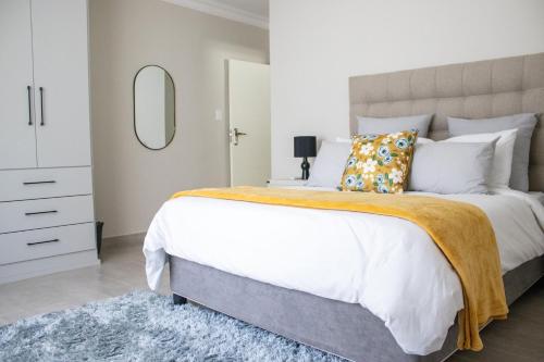 a bedroom with a large bed and a mirror at Asania Guest House in Bloemfontein