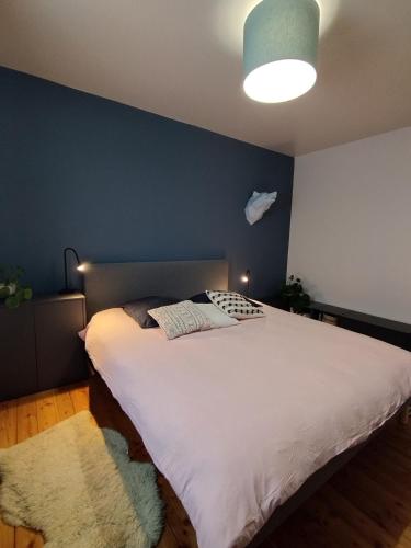 Chalet de la Cianario في فالديبلور: غرفة نوم بسرير ابيض كبير بجدار ازرق