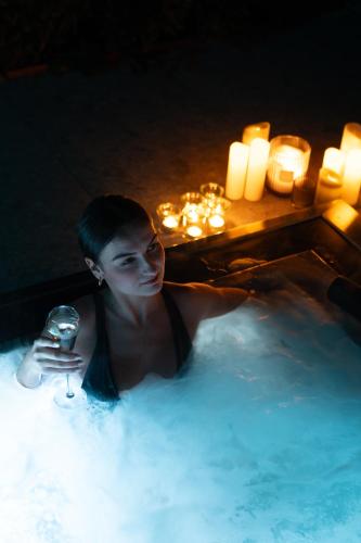 a man in a hot tub with a glass of wine at Le Pavillon M, Piscine et Spa au pied du château, Petit-Déjeuner inclus, Parking privé in Grignan