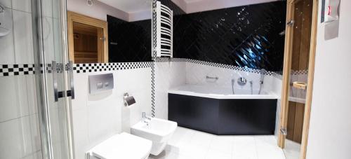 a bathroom with a sink and a tub and a toilet at Hotel Silvia Gold Gliwice in Gliwice