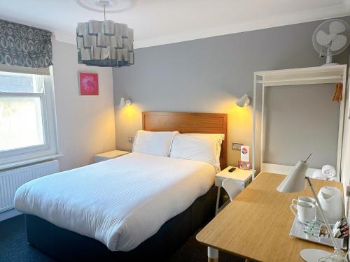 a hotel room with a large bed and a desk at Legends Hotel in Brighton & Hove