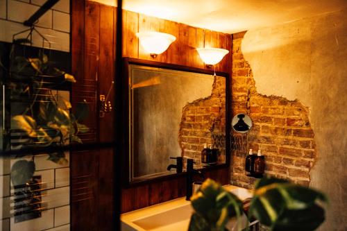 a bathroom with a sink and a mirror and a brick wall at The George & Heart House in Kent