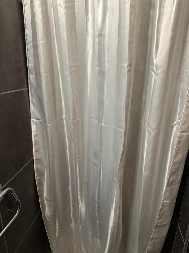 a white shower curtain in a bathroom at Chambre Indépendante Valdor in Crans-Montana