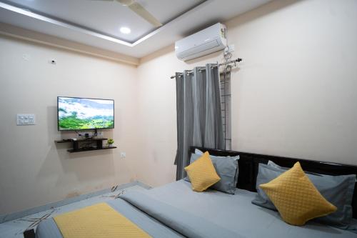a bedroom with a bed with yellow pillows and a tv at Yellow Bells Gachibowli in Hyderabad
